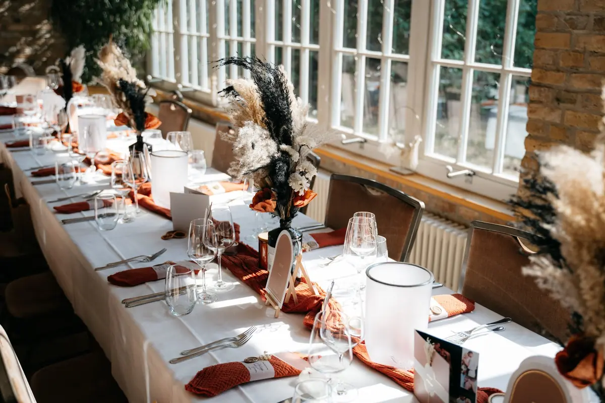 Festlich gedeckte Tafel mit Kerzen und Trockenblumen im Saal