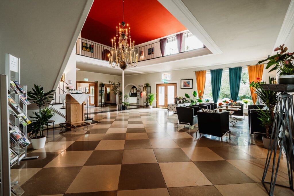 Lobby mit Schachbrettboden, Sitzgruppen und Kronleuchter im Hotel Schwarzwald in Freudenstadt