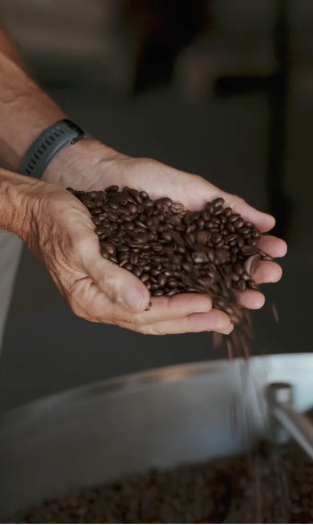 Hände voller gerösteter Kaffeebohnen über der Röstmaschine – Videostill, Seehotel Wiesler